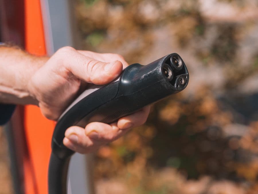 Connettore per la ricarica di un'auto elettrica tenuto in mano