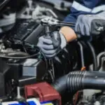 mani di meccanico con guanto con chiave inglese lavorano su un motore