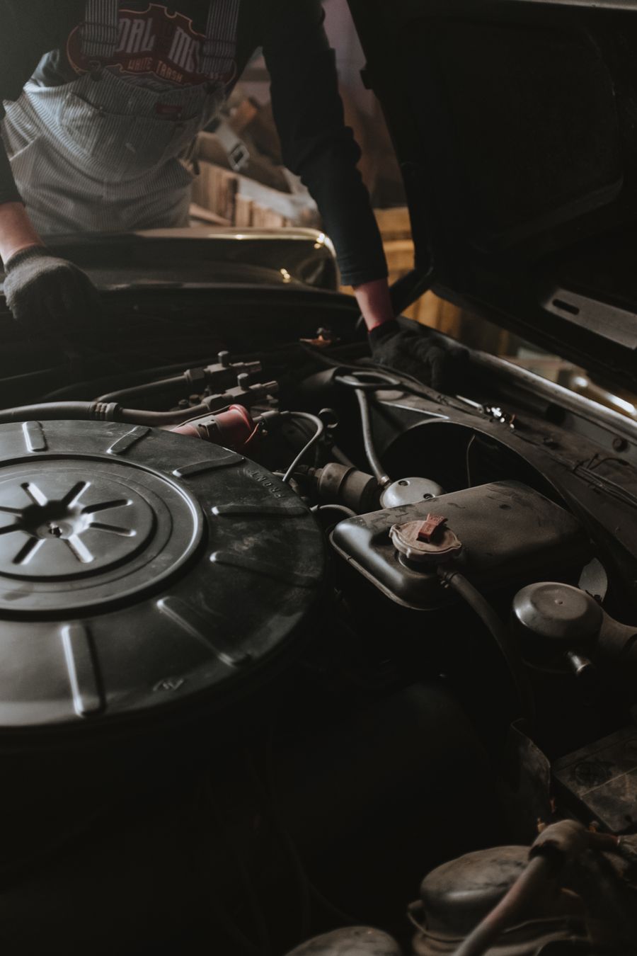Meccanico al lavoro sul vano motore di un'auto in officina